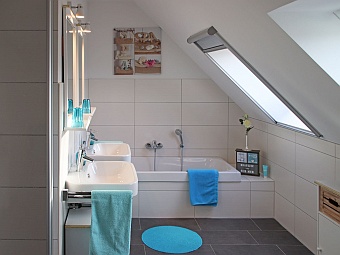 Das Bad im Dachgeschoss mit zwei Waschbecken, Badewanne und Dusche